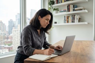 Femme concentrée travaillant sur son ordinateur dans un appartement moderne