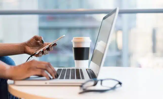 person using smartphone and MacBook